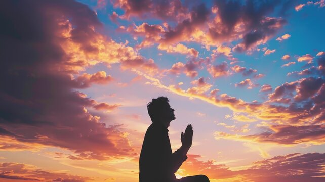 Person praying during a vibrant sunset - A person holds a prayer pose under an awe-inspiring, colorful sunset, evoking deep spirituality