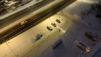 Drone photography of a small parking lot and cars covered in snow during winter night