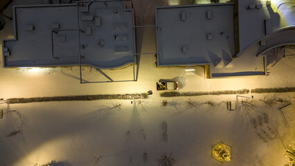 Drone photography of an apartment block and playground covered in snow during winter night