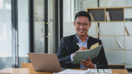 Smiling asian businessman with a notebook giving an online presentation. Professional webinar and...