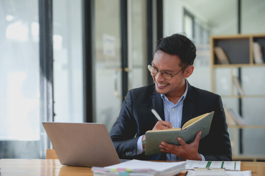 Smiling asian businessman with a notebook giving an online presentation. Professional webinar and virtual meeting concept.