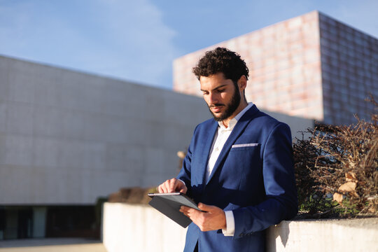 Millennial businessman using digital tablet in financial district. Hispanic ethnicity. Copyspace.