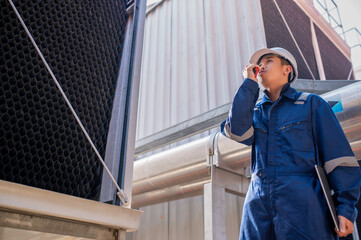 Young engineer working at large factory,Technician in protective uniform and with hardhat  checking temperature in pipes