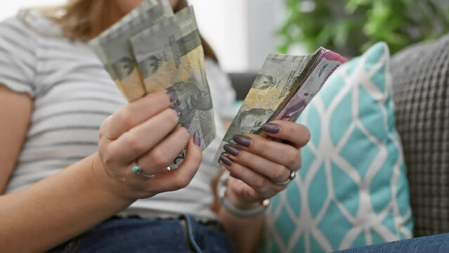 A woman at home holding indonesian rupiah banknotes, depicting finance, savings, or budgeting concepts.