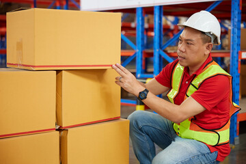 factory worker or warehouser checking corrugated boxes in the warehouse storage - obrazy, fototapety, plakaty