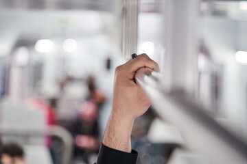Close-up of a man holding handrail traveling by subway train