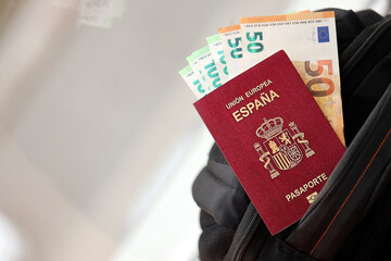 Fototapeta premium Red Spanish passport of European Union with money and airline tickets on touristic backpack close up. Tourism and travel concept