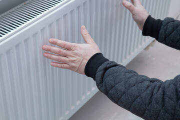Hand on the heating battery. The beginning of the heating season.