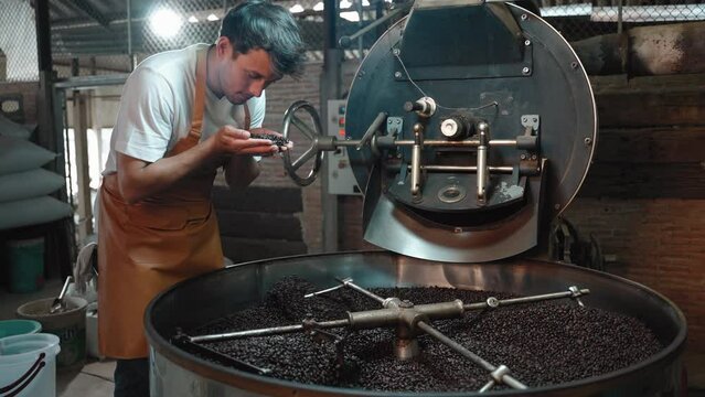 Young man smelling coffee roasted from the oven in his own factory, starting a family business, running a small business, private brands.
