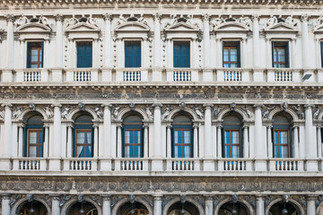 Fototapeta na wymiar Marble arcades at facade of historical building at San Marco square in Venice, Italy