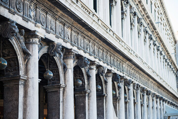 Row of arches and columns at facade of historical building at San Marco square in Venice, Italy