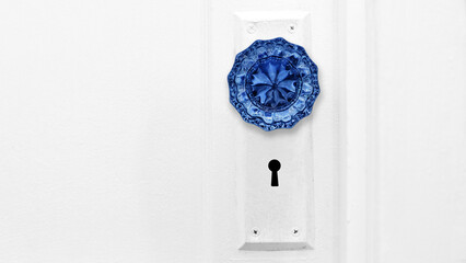 Beautiful close-up photo of a vibrant blue antique crystal door knob on a white interior door with copy space. - obrazy, fototapety, plakaty
