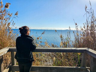 woman in a wooden gazebo, observes the blue of the Mar Menor, on a sunny day