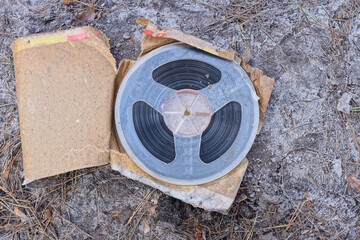 one old plastic magnetic reel for a tape recorder lies in a brown paper package on the gray ground...