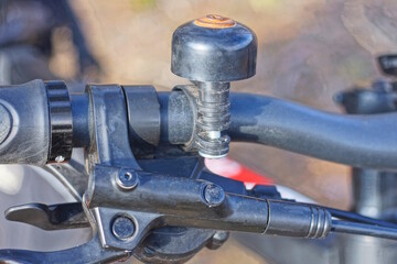 one black bicycle bell on the metal handlebar of a sports bike on the street