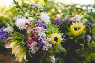 Two outdoor flower bouquets featuring light yellow sunflowers, pink snapdragons, yarrow and strawflowers