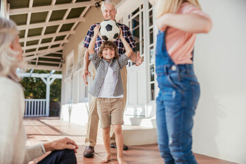 Grandparents and grandchildren having fun with a soccer ball on house porch