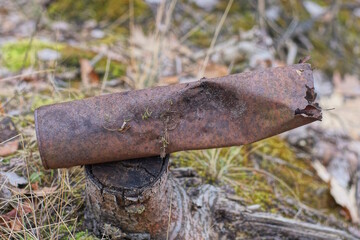 one long old brown rusty burnt metal can lies on a stump outdoors in nature