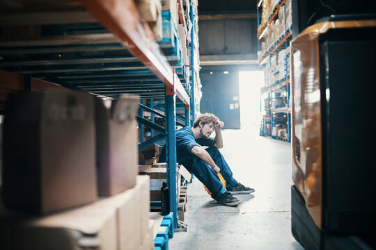 Tired young man taking break from working in warehouse