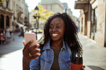 Smiling young woman using smartphone downtown