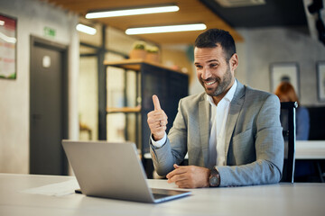 A happy businessman having an online meeting, showing a thumb up.