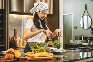 Housewife using ladle to scoop vegetable salad onto a plate after mixing fresh vegetable salad in...