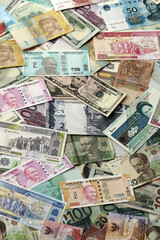 Many banknotes of different currency. Background of big amount of random money bills close up