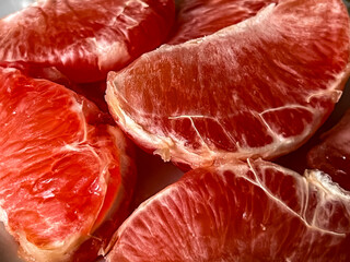 Pieces of peeled red grapefruits lying on a plate close-up