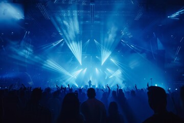 Concert stage with blue lights and audience silhouette.