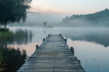 Tafelkleed Old wooden jetty on a misty lake at dawn with trees and hills in the background. Serene and mystical landscape photography. Contemplation and solitude concept for design and print with copy space © Atthasit