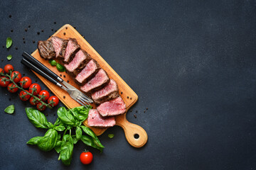 Beef with basil and tomatoes on a wooden board