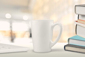 White ceramic cup and notebooks on table
