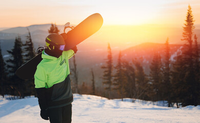 Concept snowboarding sport, trip winter day in ski resort. Man snowboarder holding snowboard on...