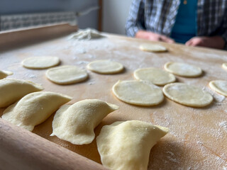 Fototapeta na wymiar Home-made dumplings, kneading the dough by hand, rolling it, cutting it out and gluing it together