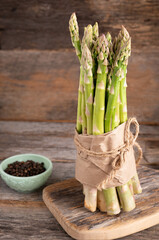 Bunch of branches of fresh green asparagus on wooden background, side view.