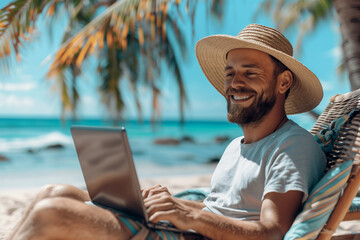 young man in a straw hat with a laptop relaxing on the beach, freelance concept