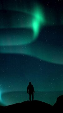 Vertical Aurora Borealis Green fluor Northern Lights and silhouette man watching. Winter landscape with polar weather in Arctic, Norway,Canada,Finland,Iceland, Sweden. Starry night sky scenery.