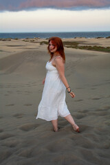 Young woman stands in the sand dunes and looks ahead