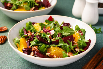 Salad with arugula, orange and beet in a plate on a green background - 752521418