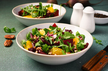 Salad with arugula, orange and beet in a plate on a green background - 752521437