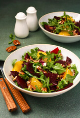 Salad with arugula, orange and beet in a plate on a green background - 752521610