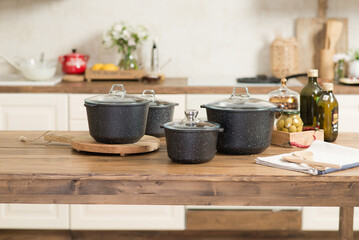 A set of pots for cooking stands in a bright kitchen