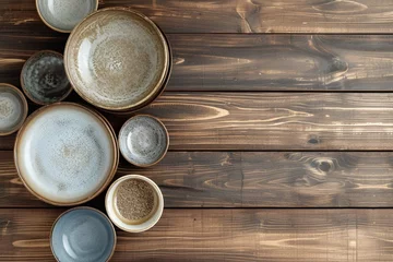  Dishes for serving and eating meals on a wooden background, space for text, top view. Modern ceramic and glass crockery, trendy tableware. © Manzoor