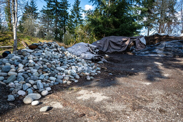 Large piles of rich mulch and river rock ready for spring gardening, outdoor public park on a sunny day
