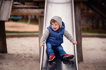 A toddler's glee is unmistakable as he slides down with a parent waiting at the end, capturing the...