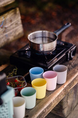 A rustic camping cook station with a pot on the stove and a vibrant array of cups, ready for a...