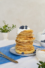 Tall stack of pancakes decorated with fresh blueberries