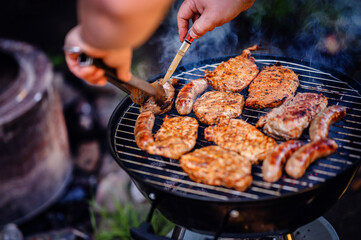 A smoky barbecue grill outdoors cooking a variety of meats, capturing the essence of summer