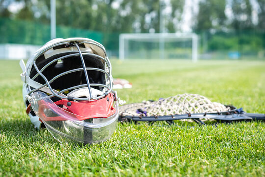 Lacrosse goalie gear on the grass field, with players in the background.
