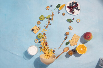 Corn flakes, fruits and berries on a blue background in sunlight